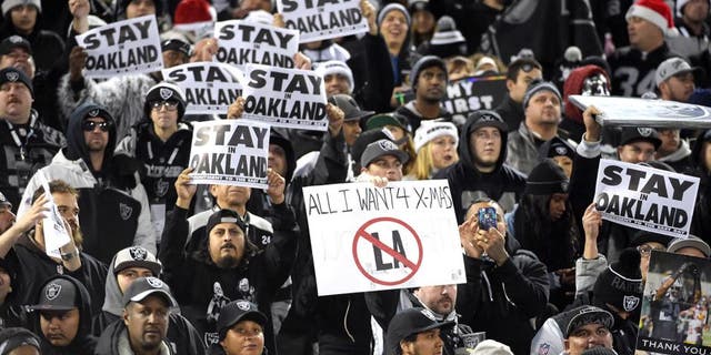 Dec 24, 2015; Oakland, CA, USA; Oakland Raiders fans hold signs that read "Stay in Oakland" in opposition of the Raiders potential move to Los Angeles during an NFL football game against the San Diego Chargers at O.co Coliseum. Mandatory Credit: Kirby Lee-USA TODAY Sports