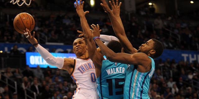 Dec 26, 2014; Oklahoma City, OK, USA; Oklahoma City Thunder guard Russell Westbrook (0) attempts a shot against Charlotte Hornets forward Michael Kidd-Gilchrist (14) and Hornets guard Kemba Walker (15) during the third quarter at Chesapeake Energy Arena. Mandatory Credit: Mark D. Smith-USA TODAY Sports