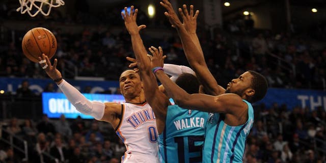 Dec 26, 2014; Oklahoma City, OK, USA; Oklahoma City Thunder guard Russell Westbrook (0) attempts a shot against Charlotte Hornets forward Michael Kidd-Gilchrist (14) and Hornets guard Kemba Walker (15) during the third quarter at Chesapeake Energy Arena. Mandatory Credit: Mark D. Smith-USA TODAY Sports