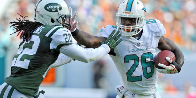 Dec 28, 2014; Miami Gardens, FL, USA; Miami Dolphins running back Lamar Miller (26) stiff arms New York Jets cornerback Marcus Williams (22) during the first half at Sun Life Stadium. Mandatory Credit: Steve Mitchell-USA TODAY Sports