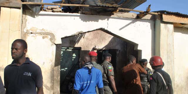 dec. 28, 2015: People gather at a damaged building following an attack by Boko Haram in Maiduguri, Nigeria