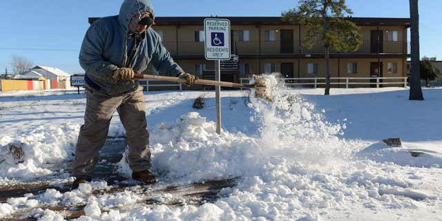 Dec. 28, 2015: Ismael Avelar, maintenance employee for the Village Place Apartments, shovels snow Monday morning from the walkway to the apartment complex office in Odessa, Texas.
