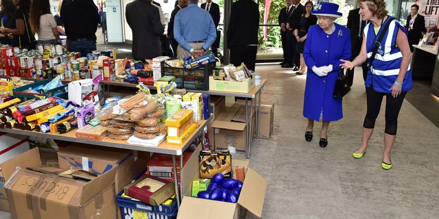 Britain's Queen Elizabeth II, second right, looks at donations made to the members of the community affected by the fire at Grenfell Tower in west London during a visit to the Westway Sports Centre which is providing temporary shelter for those who have been made homeless in the disaster, Friday June 16, 2017.