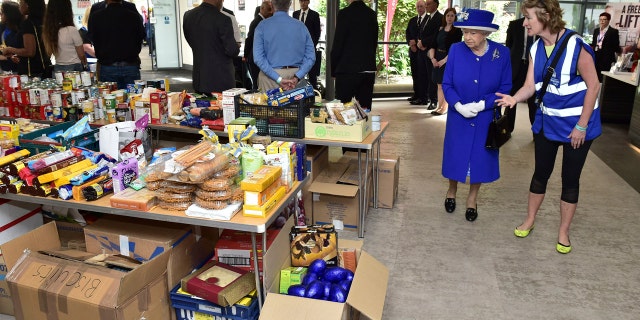 Britain's Queen Elizabeth II, second right, looks at donations made to the members of the community affected by the fire at Grenfell Tower in west London during a visit to the Westway Sports Centre which is providing temporary shelter for those who have been made homeless in the disaster, Friday June 16, 2017. Relatives of those missing after a high-rise tower blaze in London are searching frantically for their loved ones, as the police commander in charge of the investigation says he hopes the death toll will not rise to three figures. (Dominic Lipinski/Pool Photo via AP)