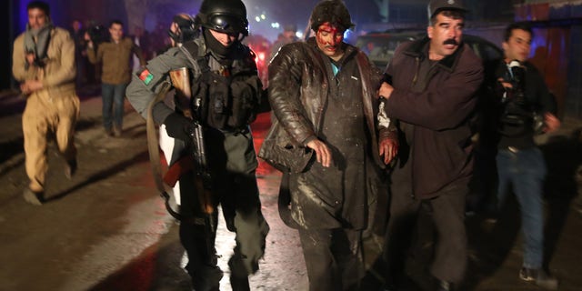Afghan police forces assist an injured man at the site of an explosion in Kabul, Afghanistan, Friday, Jan. 17, 2014. Afghan police said a suicide bomber attacked a Kabul restaurant popular with foreigners, officials. (AP Photo/Massoud Hossaini)