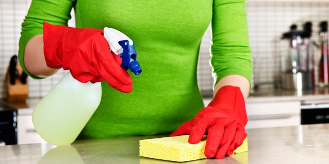 Girl cleaning kitchen with sponge and rubber gloves