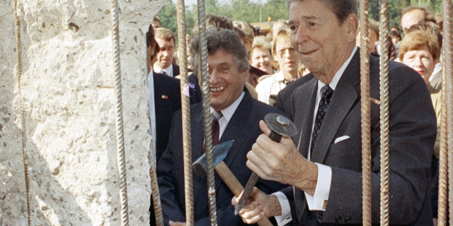 Former U.S. President Ronald Reagan holding a hammer and chisel next to the Berlin Wall on Poltsdammer Platz in East Berlin in 1990. In Berlin in 1987, Reagan challenged Soviet leader Mikhail Gorbachev to "tear down this wall," but later developed a warm relationship with his former adversary. REUTERS/Michael Probst/Files JDP - RTR3RSA