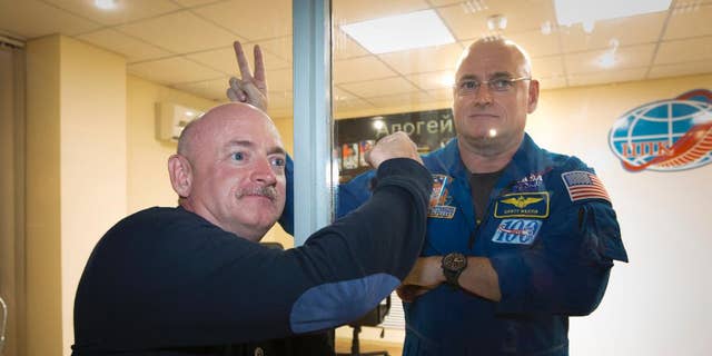 US astronaut Scott Kelly, right, member of the mission crew to the International Space Station (ISS), poses in front of a safety glass with his brother, Mark Kelly, after a conference of press in the Baikonur cosmodrome rented by Russia (Kazakhstan), Thursday, March 26, 2015.