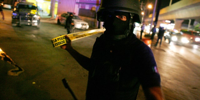 File photo. June 11, 2010: A Mexican policeman cordons off a crime scene.