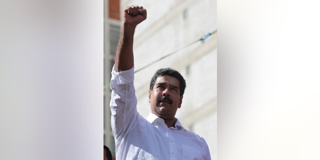In this photo provided by Miraflores Presidential Press Office, Venezuela's President Nicolas Maduro holds up fist in solidarity at a transport workers rally in Caracas, Venezuela, Tuesday, Nov. 12, 2013. Maduro says he'll present evidence in the coming hours showing how the U.S. Embassy in Caracas is plotting to destabilize the South American nation. Maduro's announcement at a pro-government rally Tuesday comes after he vowed to extend price caps that have led to long lines of bargain hunters at appliance stores across the country in recent days. (AP Photo/Miraflores Presidential Office)