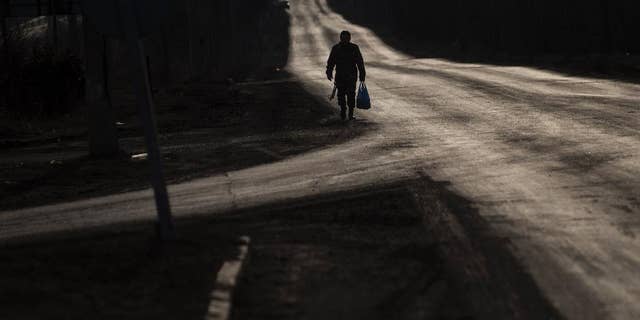 A Ukrainian serviceman walks on an empty road near Artemivsk, eastern Ukraine, Friday, March 6, 2015. Ukrainian military officials say government forces are withdrawing heavy rocket launchers from the front line with Russian-backed separatists in accordance with last month's cease-fire accord. (AP Photo/Evgeniy Maloletka)