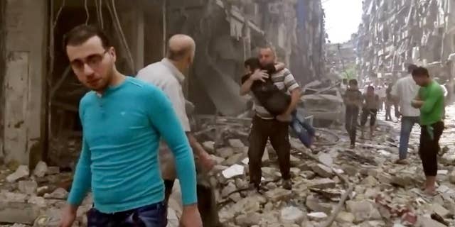 FILE - In this Thursday, April 28, 2016 image made from video and posted online from Validated UGC, a man carries a child after airstrikes hit Aleppo, Syria. A fragile cease-fire in the northern Syrian city of Aleppo has been extended for 72 hours, Russia said, as the Islamic State group battled other militant factions near the city on Saturday, May 7, 2016.  (Validated UGC via AP video, File)