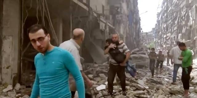 FILE - In this Thursday, April 28, 2016 image made from video and posted online from Validated UGC, a man carries a child after airstrikes hit Aleppo, Syria. A fragile cease-fire in the northern Syrian city of Aleppo has been extended for 72 hours, Russia said, as the Islamic State group battled other militant factions near the city on Saturday, May 7, 2016. (Validated UGC via AP video, File)