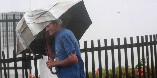 A man carrying an umbrella walks on a street as Hurricane Irma howls past Puerto Rico after thrashing several smaller Caribbean islands, in Fajardo, Puerto Rico September 6, 2017. REUTERS/Alvin Baez - RC147BEAFC70