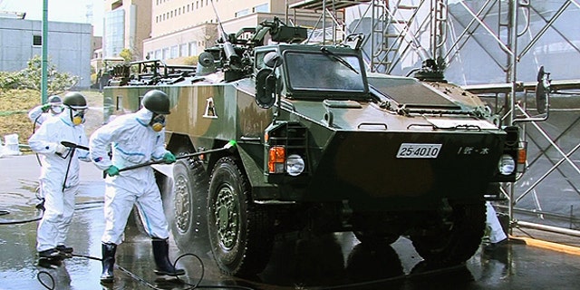 April 12: In this photo released by the Japan Defense Agency via Kyodo News, Japanese soldiers wash an armored vehicle to remove potential radiation contamination at J-Village, a soccer training complex now serving as an operation base for those battling Japan's worst nuclear disaster, northeastern Japan.