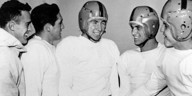 FILE - In this Dec. 11, 1953, file photo, Notre Dame player John Lattner, center, winner of the 1953 Heisman tropy and second-time winner of the Maxwell trophy, receives congratulations from teammates at practice in South Bend, Ind. Lattner, who helped lead Notre Dame to a 9-0-1 record and a No. 2 ranking in Frank Leahy's final year as coach, has died at 83. His death was confirmed Saturday, Feb. 13, 2016, by Notre Dame. (AP Photo/File)