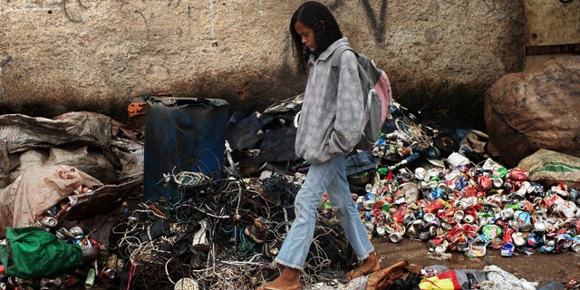 JARDIM GRAMACHO, BRAZIL - DECEMBER 09: A girl walks through a portion of the Jardim Gramacho waste disposal site on December 9, 2009 in Jardim Gramacho, Brazil. Referred to as the largest open-air landfill in Latin America, the waste disposal site of Jardim Gramacho proesses up to 9,000 pounds of trash daily from Rio de Janerio. The landfill provides a livelihood for over 1000 trash pickers who make an average daily wage of $20 separating the trash from paper, cans and plastics that are then sold as recyclables. Gramacho opened in 1978 and is said to have reached its trash capacity years ago. The landfill is currently set to close in 2012 to avert an environmental disaster but jeopardizing the work of the 1,300 trash pickers left who have few other employment options. (Photo by Spencer Platt/Getty Images)