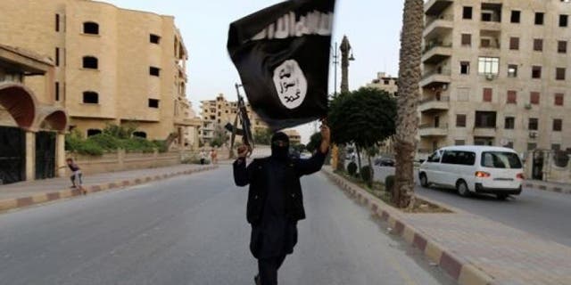 Un militante de ISIS marcha con una bandera y un arma de fuego en esta foto de archivo. 