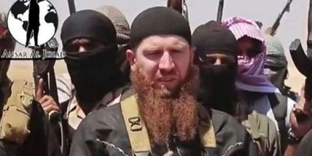 June 28, 2014: This image made from undated video posted on a social media account frequently used for communications by the ISIS, which has been verified and is consistent with other AP reporting, shows Abu Umar al-Shishani standing next to the group's spokesman among a group of fighters as they declare the elimination of the border between Iraq and Syria.