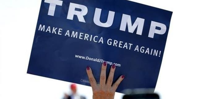 In this March 19, 2016 file photo, a supporter holds a sign as Republican presidential candidate Donald Trump speaks during a campaign rally in Fountain Hills, Ariz.