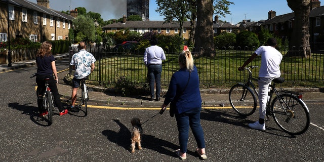 People look at smoke billowing from a tower block severly damaged by a serious fire, in north Kensington, West London, Britain June 14, 2017. REUTERS/Toby Melville - RTS1704D