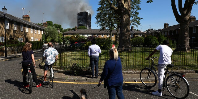People look at smoke billowing from a tower block severly damaged by a serious fire, in north Kensington, West London, Britain June 14, 2017. REUTERS/Toby Melville - RTS1704D