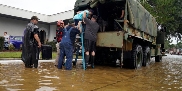 Volunteers load people into a collector's vintage military truck to evacuate them from flood waters from Hurricane Harvey in Dickinson, Texas, U.S. August 27, 2017.