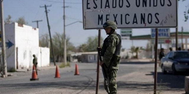 In this photo taken April 7, 2010, soldiers guard near the U.S.-Mexico border in Caseta border town, Valle de Juarez, northern Mexico. Hundreds of families are fleeing the cotton-farming towns of the Juarez Valley, a stretch of border 50 miles east of Ciudad Juarez. In a new strategy, Mexican drug cartels seeking to minimize interference with their operations are using terror to empty the entire area. (AP Photo/Guillermo Arias)