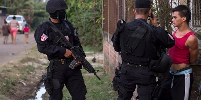 In this April 1, 2015 photo, a man is detained by police special forces in the town of San Juan Opico, El Salvador.