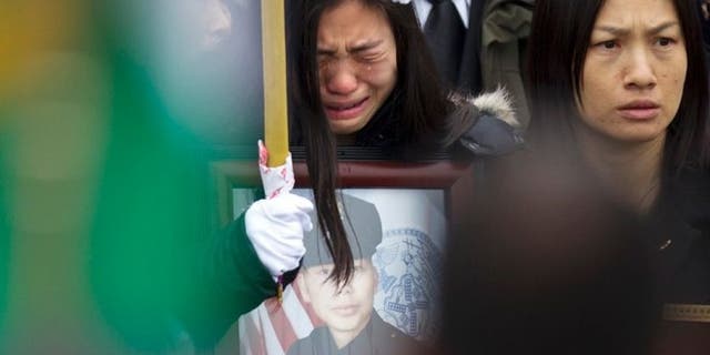 Widow Pei Xia Chen reacts while clutching a photo of slain New York Police Department officer Wenjian Liu as his casket departs his funeral in the Brooklyn borough of New York January 4, 2015. (REUTERS/Carlo Allegri)