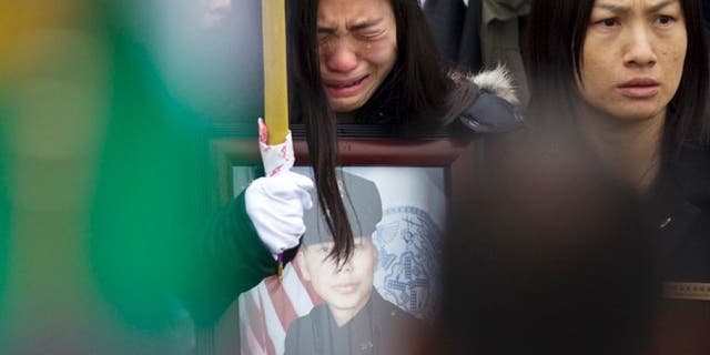 Widow Pei Xia Chen reacts while clutching a photo of slain New York Police Department officer Wenjian Liu as his casket departs his funeral in the Brooklyn borough of New York January 4, 2015. (REUTERS/Carlo Allegri)
