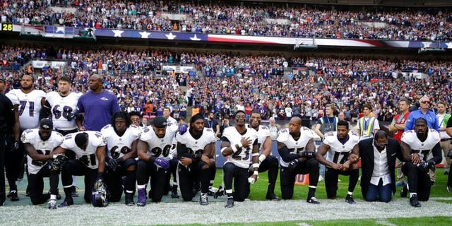 Baltimore Ravens players, including former player Ray Lewis, second from right, kneel down during the playing of the U.S. national anthem before an NFL football game against the Jacksonville Jaguars at Wembley Stadium in London on Sunday.