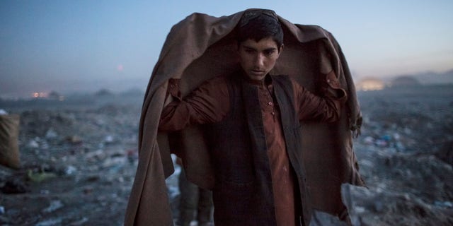 KABUL, AFGHANISTAN - NOVEMBER 14: An Afghan Pashtun boy, who said he was forced from the troubled province of Baglan due to threats from the Taliban, looks on as he winds up for the day after scavenging for recyclables at a garbage dump site on November 14, 2012 in Kabul, Afghanistan. Children working at the garbage site in Kabul said they can make up to 90 Afghans (USD $1.75) per day collecting cans and other recyclable materials for sale. If they were to stay and work in their home province, with limited options for employment, and join the Police or Army, the Taliban threatened they would come for them and their families, they said. (Photo by Daniel Berehulak/Getty Images)