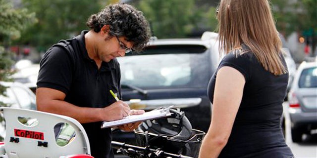 In this Sept. 9, 2011, photo, Mellissa Brown, right, a volunteer for Organizing for America, collects a signature from Jay Gupta for a petition in Columbus, Ohio, in a ballot repeal effort by opponents of the Ohio's new elections law.
