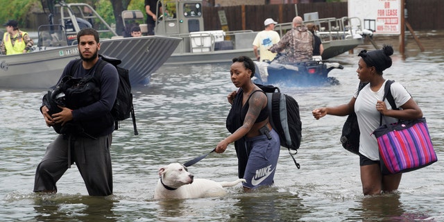 People walk through water to a staging area to evacuate from flood waters from Hurricane Harvey in Dickinson, Texas August 27, 2017.