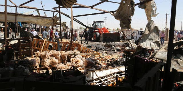 A bulldozer clears rubble at the scene of a deadly suicide car bombing at an outdoor vegetable and fruit market in a Shiite-dominated district in northeastern Baghdad, Iraq, Tuesday, July 12, 2016. The bomb on Tuesday, killed at least 10 people and injured tens of others, officials said. The developments came on the heels of two large-scale attacks claimed by the Islamic State group that killed more than 300 people last week. (AP Photo/Karim Kadim)