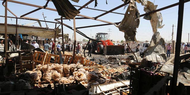 A bulldozer clears rubble at the scene of a deadly suicide car bombing at an outdoor vegetable and fruit market in a Shiite-dominated district in northeastern Baghdad, Iraq, Tuesday, July 12, 2016. The bomb on Tuesday, killed at least 10 people and injured tens of others, officials said. The developments came on the heels of two large-scale attacks claimed by the Islamic State group that killed more than 300 people last week. (AP Photo/Karim Kadim)
