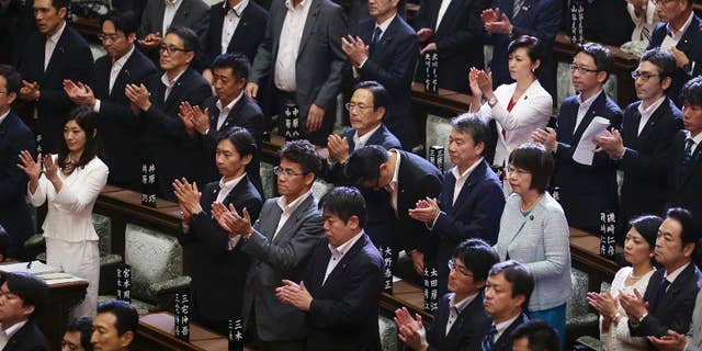Japan’s ruling party lawmakers and others who supported legislation loosening post-World War II constraints on the use of force by the military, applaud after the legislation was passed in a vote by the upper house, Tokyo, Saturday, Sept. 19, 2015. Japan's parliament approved contentious legislation to loosen constraints on the country’s military, giving it a greater role. (AP Photo/Koji Sasahara)