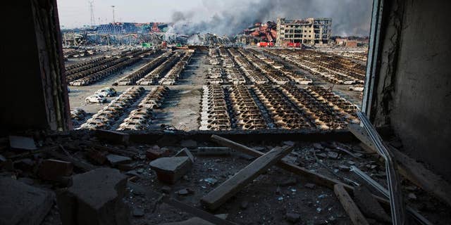FILE - In this Aug. 13, 2015 photo, a shattered window frames the site of an explosion at a port warehouse in northeastern China's Tianjin municipality. Chinese prosecutors have detained 11 government officials and company executives over a massive warehouse explosion that killed at least 139 people in the country's worst industrial disaster in recent years. (AP Photo/Ng Han Guan. File)