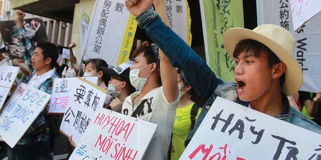 FILE - In this Aug. 10, 2016 file photo, Vietnamese activists shout slogans and hold placards reading ''Destroying the environment is killing, "left, and ''Return clean seawater to us'' during a protest to urge Formosa Plastics Group to take responsibilities for the cleanup in Vietnam, in Taipei, Taiwan. Hundreds of Vietnamese fishermen have filed claims seeking compensation from a Taiwanese steel company that acknowledged its toxic chemicals caused a massive fish kill, a local priest helping the fishermen said Tuesday, Sept. 27, 2016. (AP Photo/Chiang Ying-ying, File)