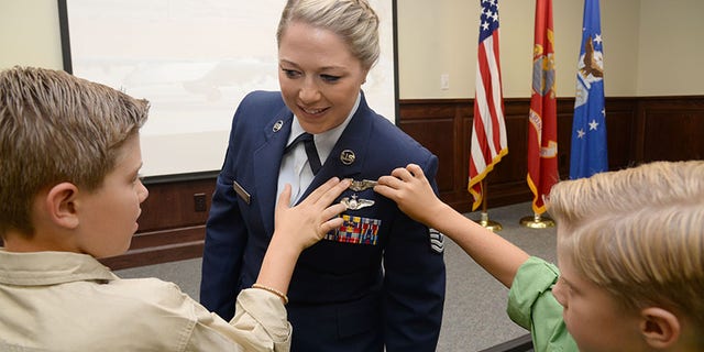 U.S. Air Force Tech. Sgt. Courtney, has her remote piloted aircraft wings pinned on by her sons David and Riley during the 558th Flying Training Squadron's Undergraduate Remotely Piloted Aircraft Training Course graduation August 4, 2017, at Joint Base San Antonio-Randolph, Texas.