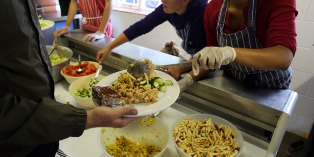 GLASTONBURY, ENGLAND - JUNE 20: Festival caterers serve lunch at Goose Hall, the on-site staff canteen, at the Glastonbury Festival of Contemporary Performing Arts site at Worthy Farm, in Pilton on June 20, 2013 in Glastonbury, England. In a weeks time, the diary farm in Somerset will be playing host to one of the largest music festivals in the world and this year features headline acts Artic Monkeys, Mumford and Sons and the Rolling Stones. Tickets to the event which is now in its 43rd year sold out in minutes and that was before any of the headline acts had been confirmed. The festival, which started in 1970 when several hundred hippies paid 1 GBP to watch Marc Bolan, now attracts more than 175,000 people over five days. (Photo by Matt Cardy/Getty Images)