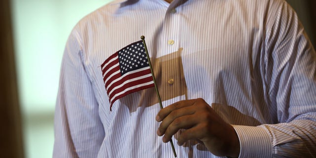 WASHINGTON, DC - JULY 03: A new U.S. citizen holds a U.S. flag during a naturalization ceremony at the Treasury Department July 3, 2013 in Washington, DC. More than 7,800 people will become citizens at more than 100 special ceremonies, as part of the United States Citizenship and Immigration Services' (USCIS) annual celebration of Independence Day, across the country and around the world from July 1 to July 5. (Photo by Alex Wong/Getty Images)