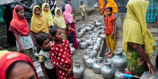 FILE - In this Dec. 3, 2016, file photo, Rohingya women and children wait in a queue to collect water at the Leda camp, an unregistered camp for Rohingya in Teknaf, near Cox's Bazar, a southern coastal district about, 296 kilometers (183 miles) south of Dhaka, Bangladesh. Newly revealed video of Myanmar police beating Rohingya Muslims in northern Rakhine state has weakened months of government claims that its forces have not committed abuses in the region since a deadly insurgent attack in October. The footage has made it more difficult for the government to say at least some abuses are not happening and sown doubts into its dismissals of more grievous allegations. (AP Photo, File)