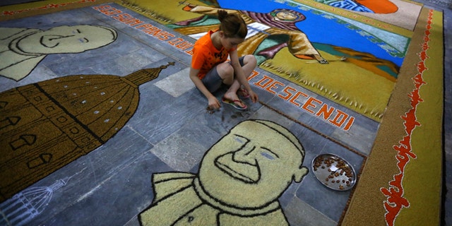 An Iraqi child works on a temporary mosaic of Pope Francis' face made from wheat, beans and lentils in Alqosh, a village of some 6,000 inhabitants about 31 miles north of Mosul, northern Iraq. (AP)