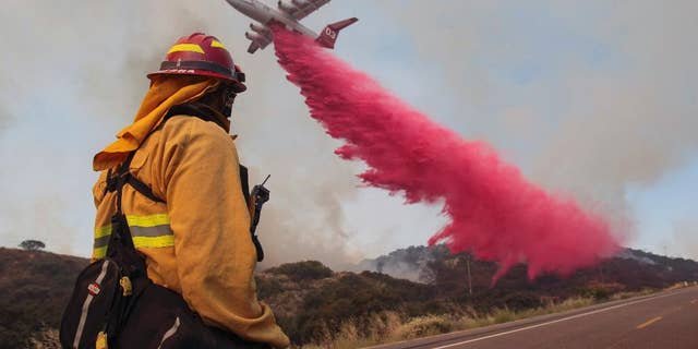Upland Fire Capt. Joe Burna watches as a tanker drops fire retardant to stop a wildfire from jumping over Highway 94 near Potrero, Calif., on Monday, June 20, 2016. (Hayne Palmour IV/San Diego Union-Tribune via AP)