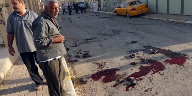 FILE - In this file photo taken Tuesday, Oct. 15, 2013, worshipers look at blood stains at the site of a bomb attack near a Sunni mosque in Kirkuk, 290 kilometers (180 miles) north of Baghdad, Iraq. The United Nations said Wednesday, Jan. 1, 2014, that violence claimed the lives of 7,818 civilians in Iraq in 2013, the highest annual death toll in years. (AP Photo/Emad Matti, File)