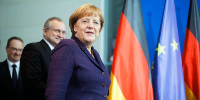 German Chancellor Angela Merkel is followed by economy advisers Lars Feld, left, and Christoph Schmidt, center, as they arrive for the hand-over ceremony of the prognosis for Germany's economy in the upcoming year at the chancellery in Berlin, Wednesday, Nov. 13, 2013. (AP Photo/Markus Schreiber)
