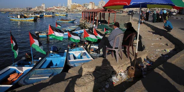 File - In this Sunday, April 17, 2016 file photo, Palestinians protect themselves from the sun at the fishermen port in Gaza City. Israel's transportation minister Yisrael Katz said he is pushing for the construction of an "artificial island" off the coast of Hamas-ruled Gaza to alleviate hardship in the blockaded coastal strip.With Israel and Egypt maintaining a naval blockade of Gaza, the Palestinians have long been pleading for a port to connect them to the rest of the world. (AP Photo/Adel Hana, File)