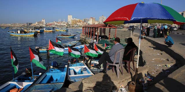 File - In this Sunday, April 17, 2016 file photo, Palestinians protect themselves from the sun at the fishermen port in Gaza City. Israel's transportation minister Yisrael Katz said he is pushing for the construction of an "artificial island" off the coast of Hamas-ruled Gaza to alleviate hardship in the blockaded coastal strip.With Israel and Egypt maintaining a naval blockade of Gaza, the Palestinians have long been pleading for a port to connect them to the rest of the world. (AP Photo/Adel Hana, File)